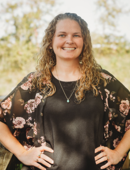 A person smiling with a floral shirtDescription automatically generated